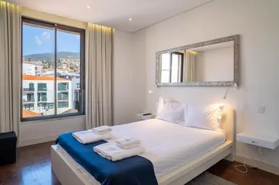 a bedroom with a bed with a mirror and a window at GuestReady - Perfect home in the city centre in Funchal