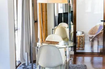 a glass table with white chairs and a mirror at GuestReady - Perfect home in the city centre in Funchal