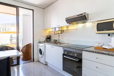 a kitchen with white cabinets and a washer and dryer at GuestReady - Perfect home in the city centre in Funchal