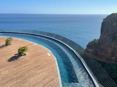 a swimming pool with the ocean in the background at Oceanfront Elegance Madeira Retreat in Câmara de Lobos