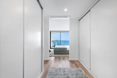 a hallway with white walls and a bedroom with a view of the ocean at Oceanfront Elegance Madeira Retreat in Câmara de Lobos