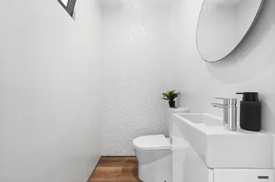 a white bathroom with a toilet and a sink at Oceanfront Elegance Madeira Retreat in Câmara de Lobos