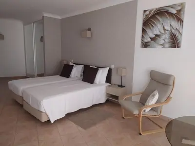 a bedroom with a white bed and a chair at Costamar in Lagos