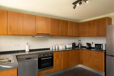 a kitchen with wooden cabinets and stainless steel appliances at Casa Pimenta in Fajã da Ovelha in Prazeres