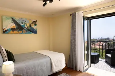 a bedroom with a bed next to a balcony at Casa Pimenta in Fajã da Ovelha in Prazeres
