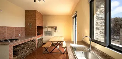 a kitchen with a fireplace and a sink in a room at Casa Pimenta in Fajã da Ovelha in Prazeres