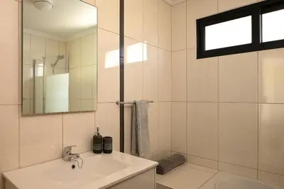 a white bathroom with a sink and a mirror at Casa Pimenta in Fajã da Ovelha in Prazeres