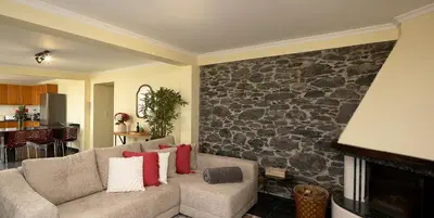 a living room with a couch and a stone wall at Casa Pimenta in Fajã da Ovelha in Prazeres