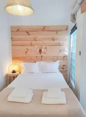 a bedroom with a large white bed with a wooden headboard at Boho Bispo Apartments in Vila do Bispo