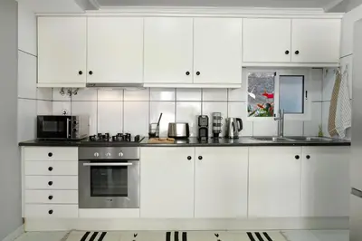 a white kitchen with white cabinets and a microwave at Madeira Funchal Stay in Funchal