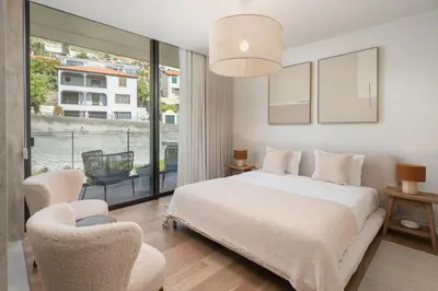 a bedroom with a white bed and two chairs at Savoy Monumentalis III by An Island Apart in Funchal