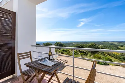 a table and chairs on a balcony with a view at Alto da Lua - Aljezur in Bordeira