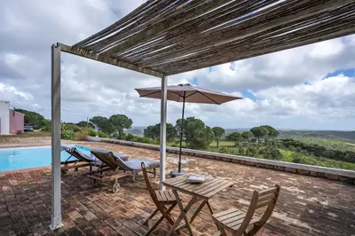 a patio with two chairs and a table at Alto da Lua in Bordeira
