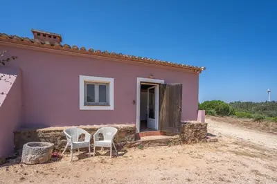a pink house with two chairs in front of it at Casa da Lua in Aljezur