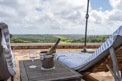 a bottle of wine in a bucket on a table with a glass at Casa da Lua in Aljezur