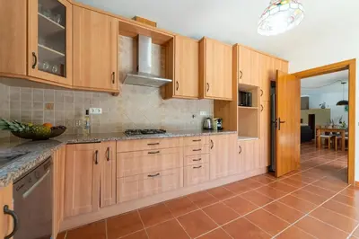 a kitchen with wooden cabinets and a tile floor at Villa Azure Family & Surf Escape in Aljezur