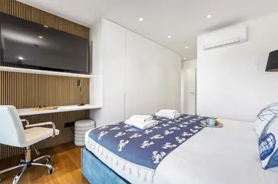 a bedroom with a bed and a chair and a tv at Apartment Bay View - By WeHost in Funchal