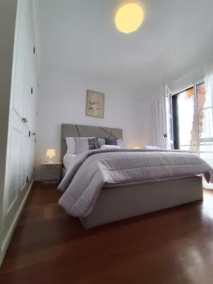 a white bedroom with a large bed and a window at The Garajau Views in Caniço