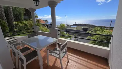 a balcony with a table and chairs and the ocean at The Garajau Views in Caniço