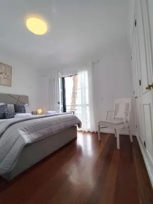 a white bedroom with a large bed and a window at The Garajau Views in Caniço