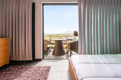 a woman sitting at a table looking out the window of a hotel room at Rosa Villa Porto Santo by YOUR KEY in Porto Santo