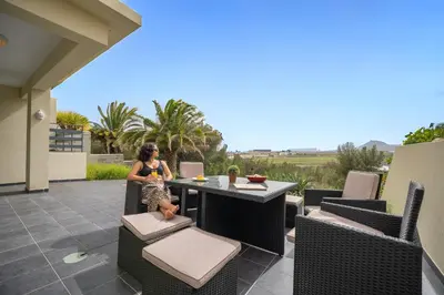 a woman sitting at a table on a patio at Rosa Villa Porto Santo by YOUR KEY in Porto Santo