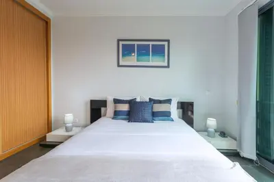 a bedroom with a large white bed with blue pillows at Rosa Villa Porto Santo by YOUR KEY in Porto Santo
