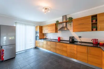 a kitchen with wooden cabinets and a stainless steel refrigerator at Rosa Villa Porto Santo by YOUR KEY in Porto Santo
