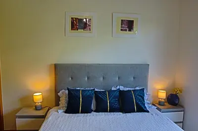a bedroom with a bed with blue pillows and two lamps at Art House Madeira I in Caniço