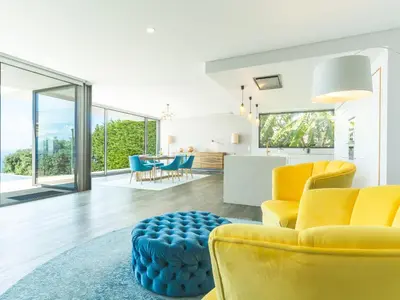 a living room with yellow chairs and a blue ottoman at Villa Primavera by Atlantic Holiday in Calheta