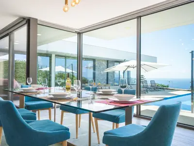 a dining room with a table and chairs with a view of the ocean at Villa Primavera by Atlantic Holiday in Calheta