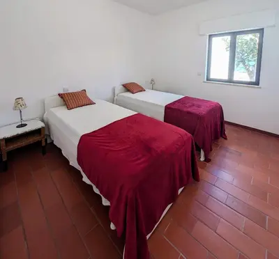 two beds with red sheets in a room at Casa Margarida in Vila do Bispo