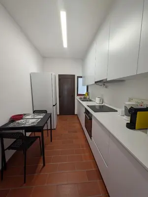a kitchen with a table and a white refrigerator at Casa Margarida in Vila do Bispo