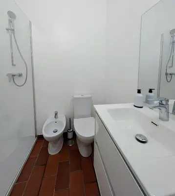 a white bathroom with a toilet and a sink at Casa Margarida in Vila do Bispo