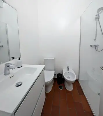 a white bathroom with a toilet and a sink at Casa Margarida in Vila do Bispo