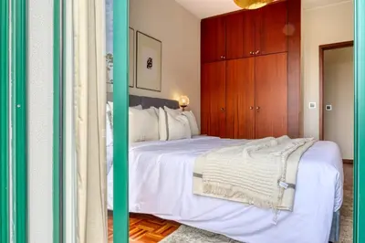 a bedroom with a white bed with a wooden cabinet at Refúgio no Funchal, a Home in Madeira in Funchal