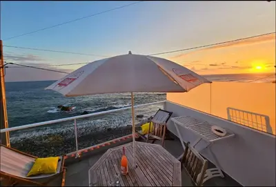 a balcony with an umbrella and a table and chairs at Ocean view in Paul do Mar
