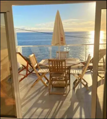 a balcony with chairs and a table and a sailboat at Ocean view in Paul do Mar