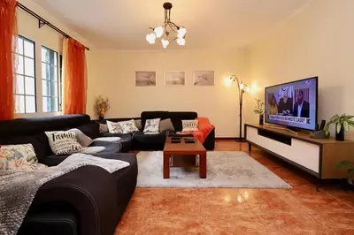 a living room with a black couch and a tv at Villa Rose by AnaLodges in Senhora do Rosário