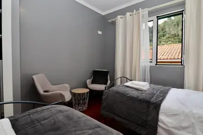 a bedroom with a bed and two chairs and a window at Villa Rose by AnaLodges in Senhora do Rosário