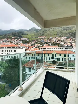a balcony with a chair and a view of a city at Amazing Views in Machico in Machico