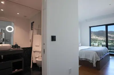 a bedroom with a bed and a bathroom with a sink at Diamond Ocean View by LovelyStay in Funchal