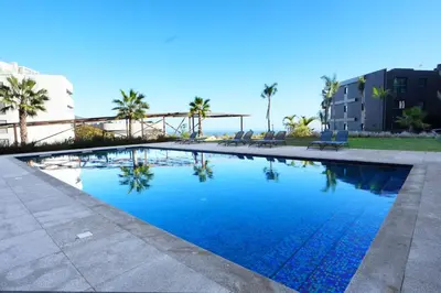 a large swimming pool with palm trees and buildings at Diamond Ocean View by LovelyStay in Funchal