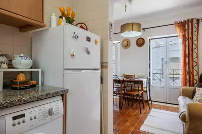 a kitchen with a white refrigerator and a dining room at Burgau - A Casa dos Avós in Burgau