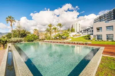 a swimming pool with chairs and a building at Oceans Whisper by Homie in Funchal