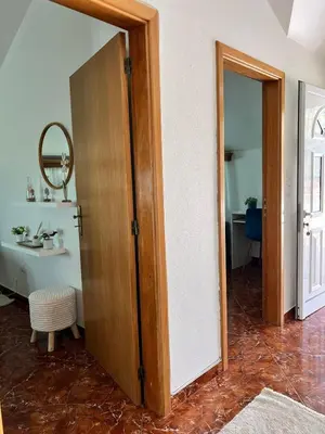 a bathroom with a wooden door and a mirror at Maria apartment in Ponta do Sol