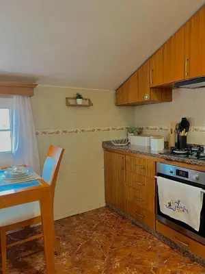 a kitchen with wooden cabinets and a stove top oven at Maria apartment in Ponta do Sol