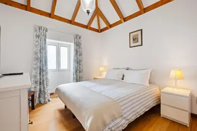 a white bedroom with a bed and a window at Quinta da Fonte in Prazeres