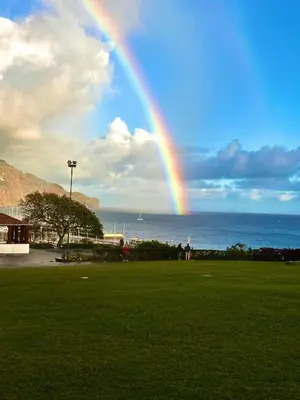 a rainbow in the sky over a field with the ocean at Villa Michelangelo in Câmara de Lobos