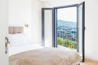a bedroom with a bed and a large window at Cocoon House in Canhas